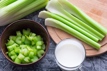 fresh celery sliced into a bowl and a glass of kefir on the table, dietary products