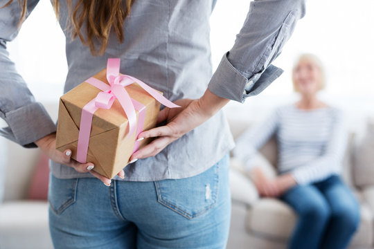 Woman Holding Gift Box Behind The Back For Her Mother