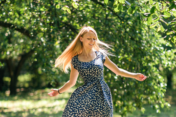 Fototapeta na wymiar Happy woman with beautiful blonde hair smiling and dancing in the summer park. The life changing magic