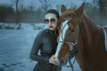 Obraz premium Fashionable woman hugging a horse's head.
