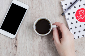 Business and office concept - black and white polka dot cover notebook, smartphone and cup of black coffee on wooden table. top view.
