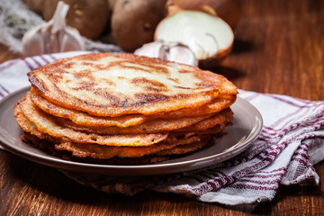 Stack of potato pancakes on a wooden table. In the background po