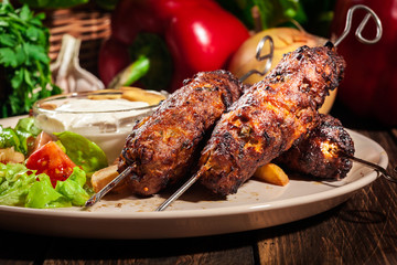 Grilled shish kebab served with fried chips and salad