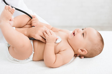 Doctor examining little baby with stethoscope in clinic.