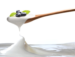 Plain yogurt on a spoon with fresh blueberries on top hanging above of plain yogurt isolated on...