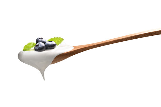 Plain yogurt on a spoon with fresh  blueberries on top isolated on white background