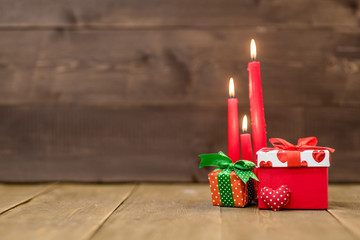 Gift boxes with candles on wooden background with empty space for text