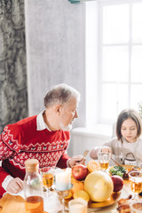 grandparent is talking with his adorable granddaughter.while having dinner . close up shot.