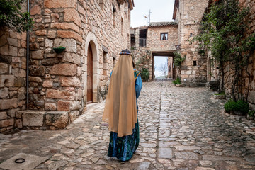 Mujer con vestido árabe caminando por una calle de la aldea medieval de Ciurana o Siurana 