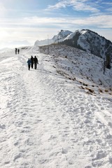Fototapeta premium People walking down the path in the mountains in winter