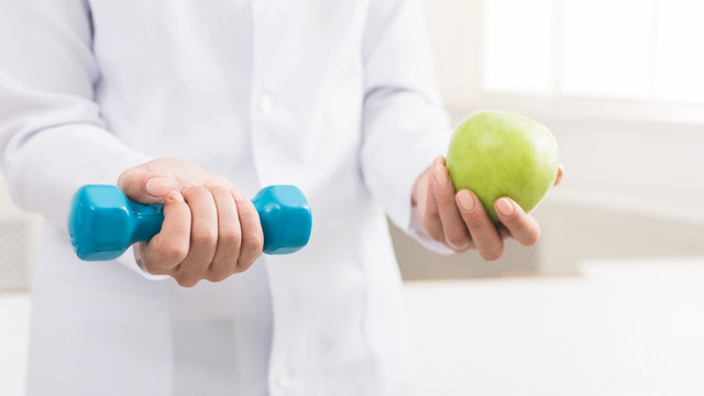 Doctor hands with green apple and dumbbell