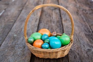 Colorful Easter egg in the basket on wooden background