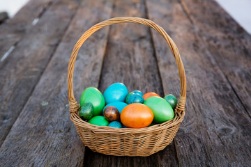 Colorful Easter egg in the basket on wooden background