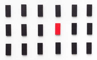 Red wooden block between black ones on white