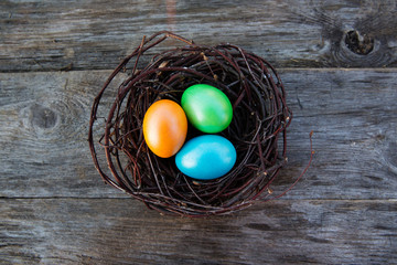 Colorful Easter egg in the nest on wooden background