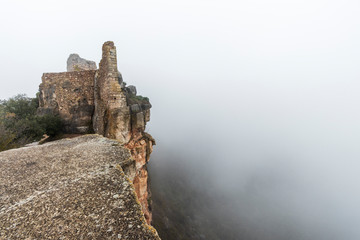Ruinas en la niebla del castillo de la ciudad medieval de Ciurana o Siurana sobre el riscal de la Sierra de la Gritella