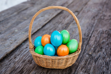 Colorful Easter egg in the basket on wooden background