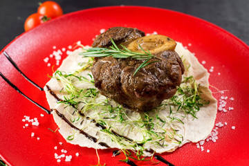 Grilled meat steak on pita leaf in a red plate