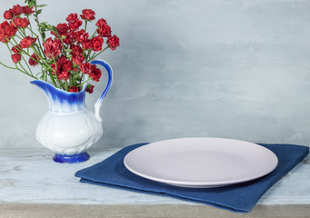 Empty plate on tablecloth on wooden table over grunge blue background