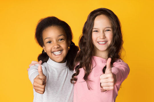Best friends showing thumbs up on studio background