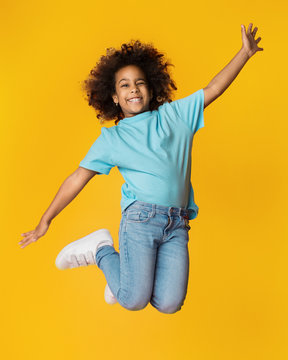 Little african-american girl jumping over studio background