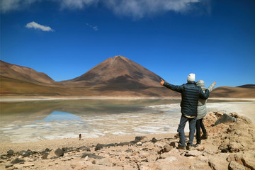 Fototapeta premium Young Tourist Couple Very Excited to See the Color of Water in the Lake Changing, Laguna Verde or Green Lake, Potosi, Bolivia 