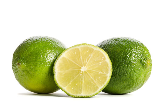 two limes with half of a juicy lime isolated on white background