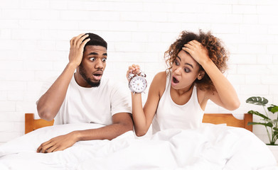 Confused couple missed ringing of alarm clock in bed
