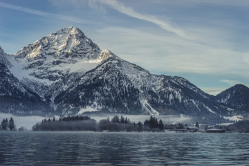Fototapeta na wymiar Winterliches Alpenpanorama mit Spiegelung von Berggipfel im See, Heiterwanger See, Tirol, Österreich