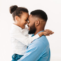 Father hugging with daughter, touching foreheads in studio - obrazy, fototapety, plakaty