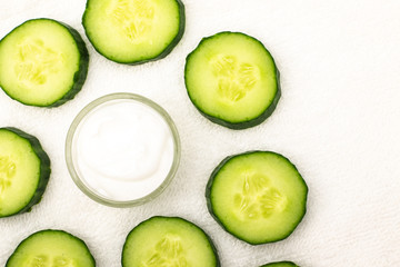 Background from cream and sliced ​​cucumbers on a white towel	