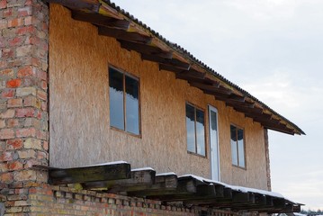 brown facade of a wooden rural house with windows against the sky