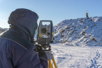 Surveyor and assistant conduct a topographical survey in the winter for cadastral work