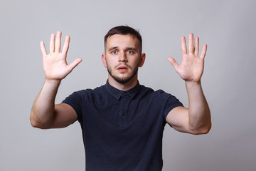 Studio portrait of a young man keep hands up before him with the expression 