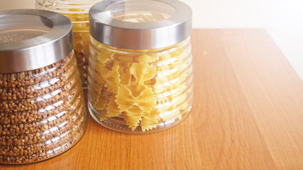 Pasta and bukwheat meals. Healthy cooking in glass containers on wooden table.
