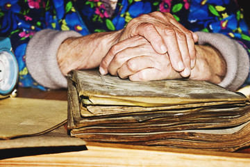 Old wrinkled hands on a time-worn book close up