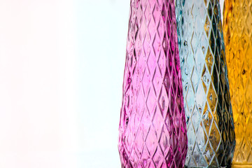Three vases of colored glass with a pattern, close-up, isolated on a light background.