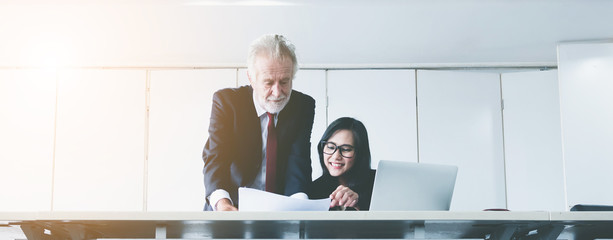 Senior businessman coaches work for young business woman