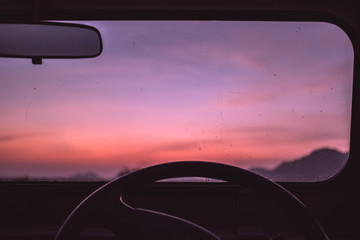Pink sunset viewed through car windscreen with copy space