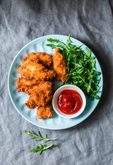 Deep-fried bread crumbs fried chicken fillet with ketchup and salad - delicious appetizer, tapas on grey background, top view