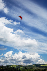 Paraglider flying over mountains during summer day