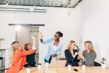 diversity, race, height, success and people concept - multi-ethnic group of happy women clapping hands and giving high five at jubilation at success or victory.