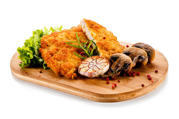 Fried pork chop with champignon on cutting board on white background