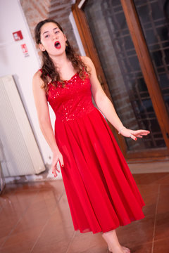 Young singer with voice (singing) without a microphone. Teenage girl with red  dress with sequins without sleeves. Singing concept. Fashion design. foto  de Stock | Adobe Stock