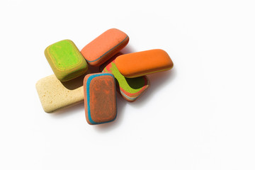 Multicolor rubbers on a white background like stones. A group of erasers stacked like a mountain