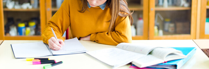 Young female college student in chemistry class, writing notes. Focused student in classroom. Authentic Education concept.