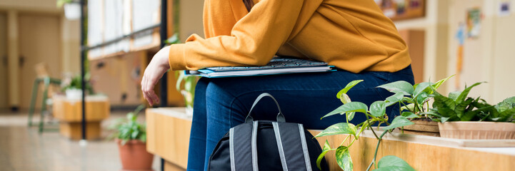 Young unrecognisable depressed lonely female college student sitting in the hallway at her school....