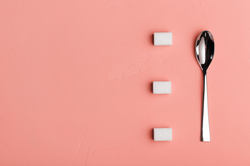 Spoon and sugar cubes on living coral background, the view from the top with place for your text. Conceptual food photos