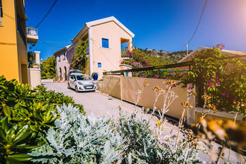 Vacation travel with car concept. Rental hired car in the narrow picturesque street of small greek town. Discover Mediterranean Islands. Summer time holiday trip