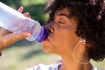 Fitness african model with a water bottle in the park - Imagem